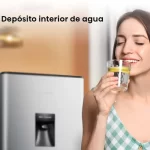 Mujer disfrutando de un vaso de agua fresca servida desde el dispensador de la nevera Hisense 179L BC179R/HC1 con depósito interior.